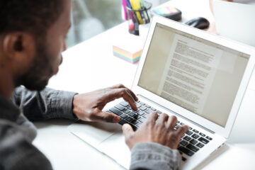 Científico revisando un manuscrito en su ordenador, mostrando la importancia de publicar artículos científicos